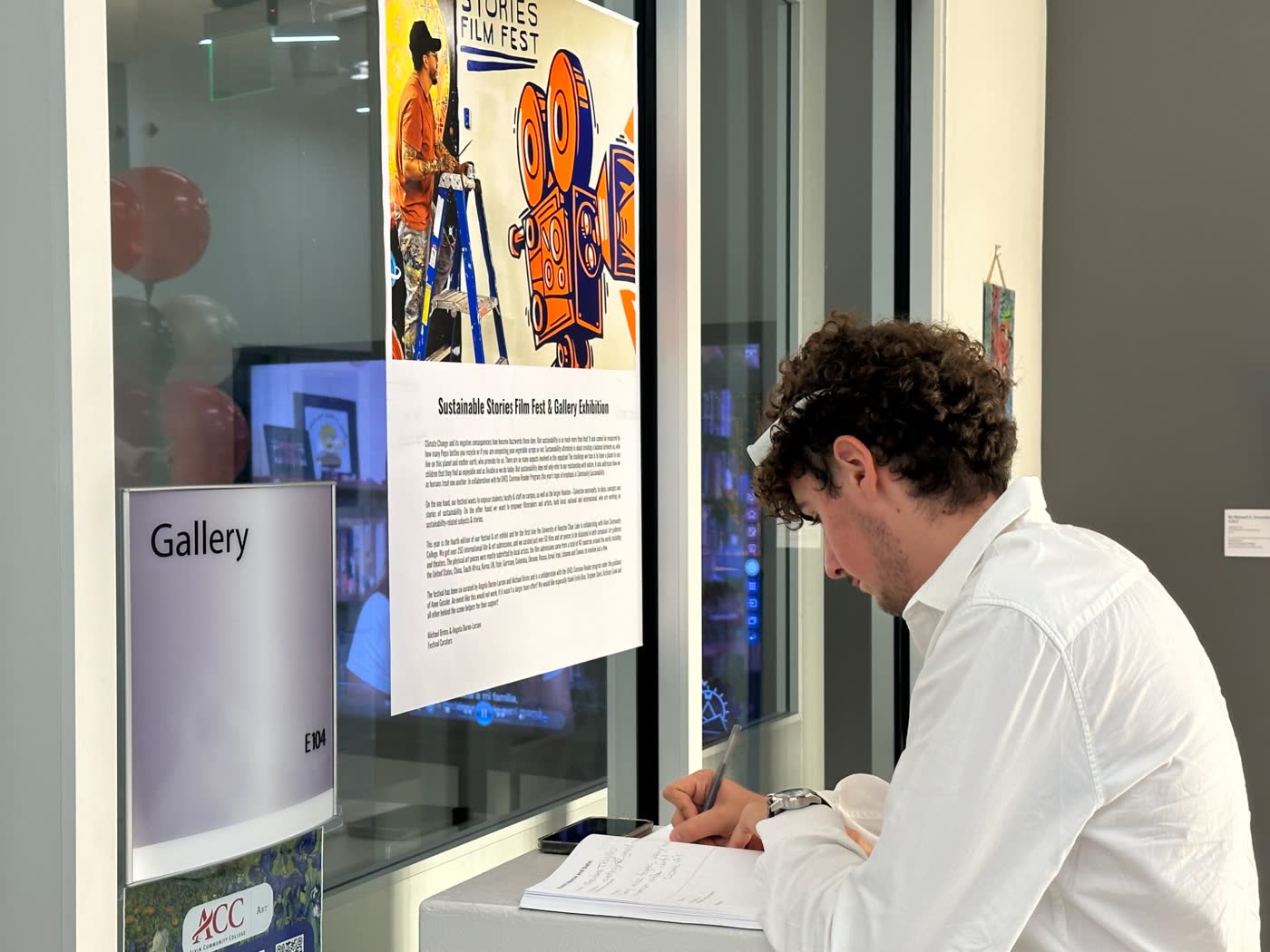A visitor writing beside the entrance to the Alvin College gallery during the 2024 festival