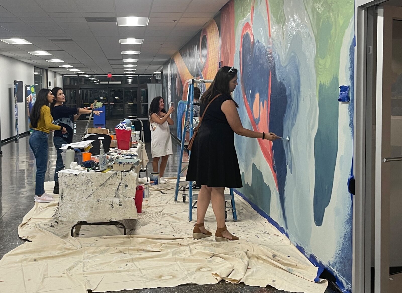 Artist and students painting a participatory mural