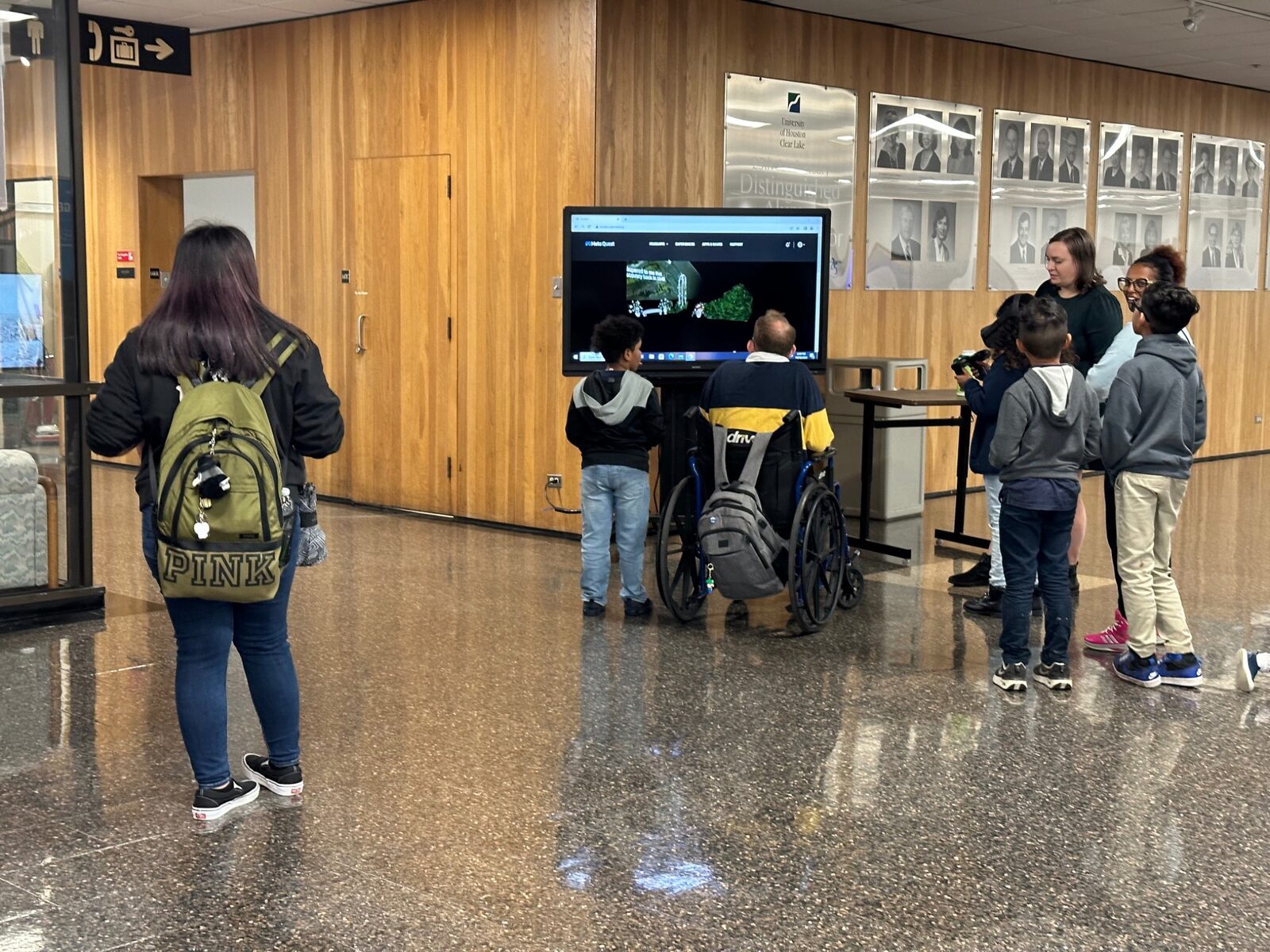 Visitors viewing an interactive screen in a campus hallway