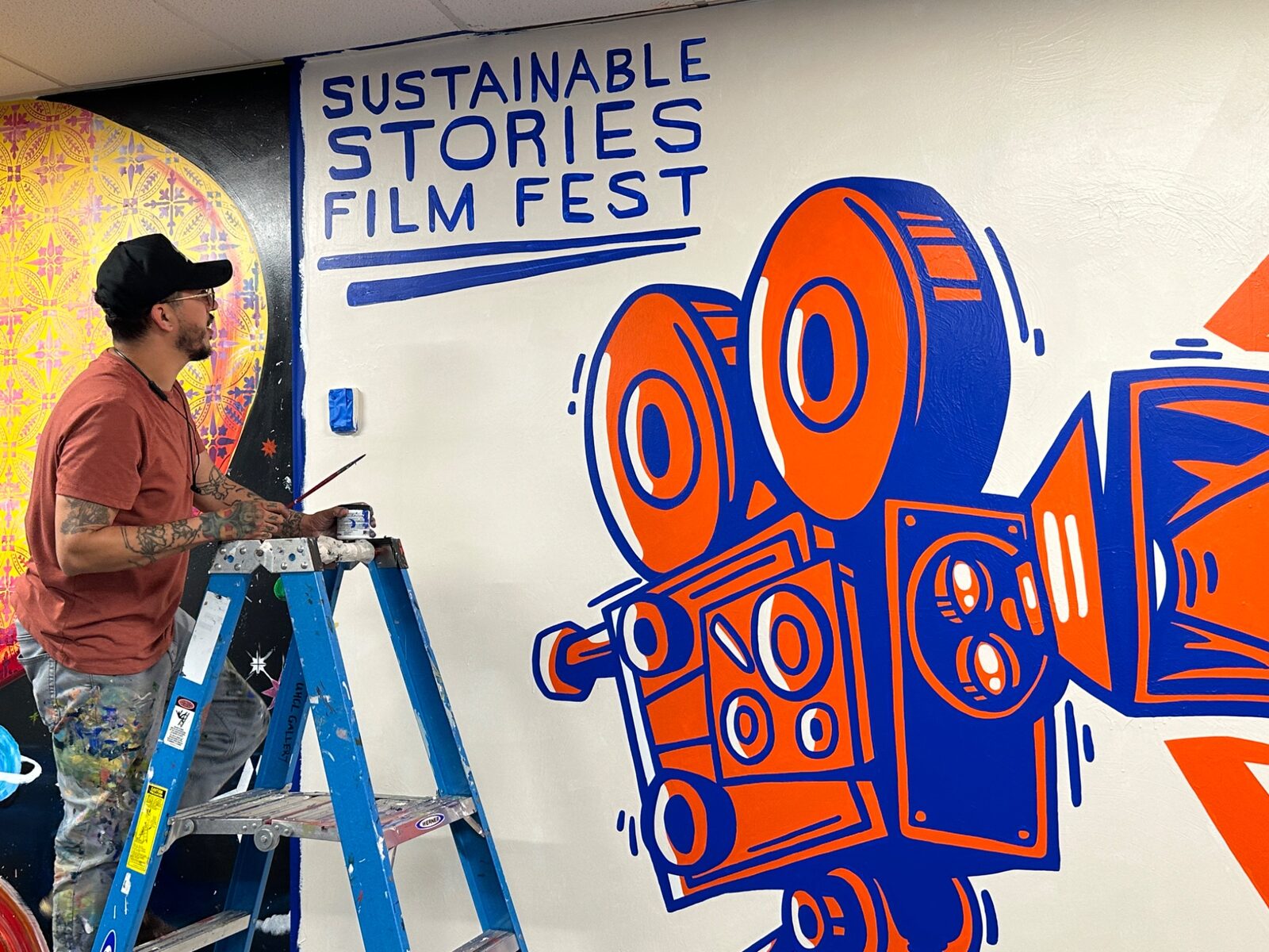 Artist painting the Sustainable Stories mural